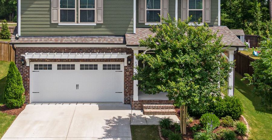 A garage, driveway and trimmed foundation shrubs at a suburban home.