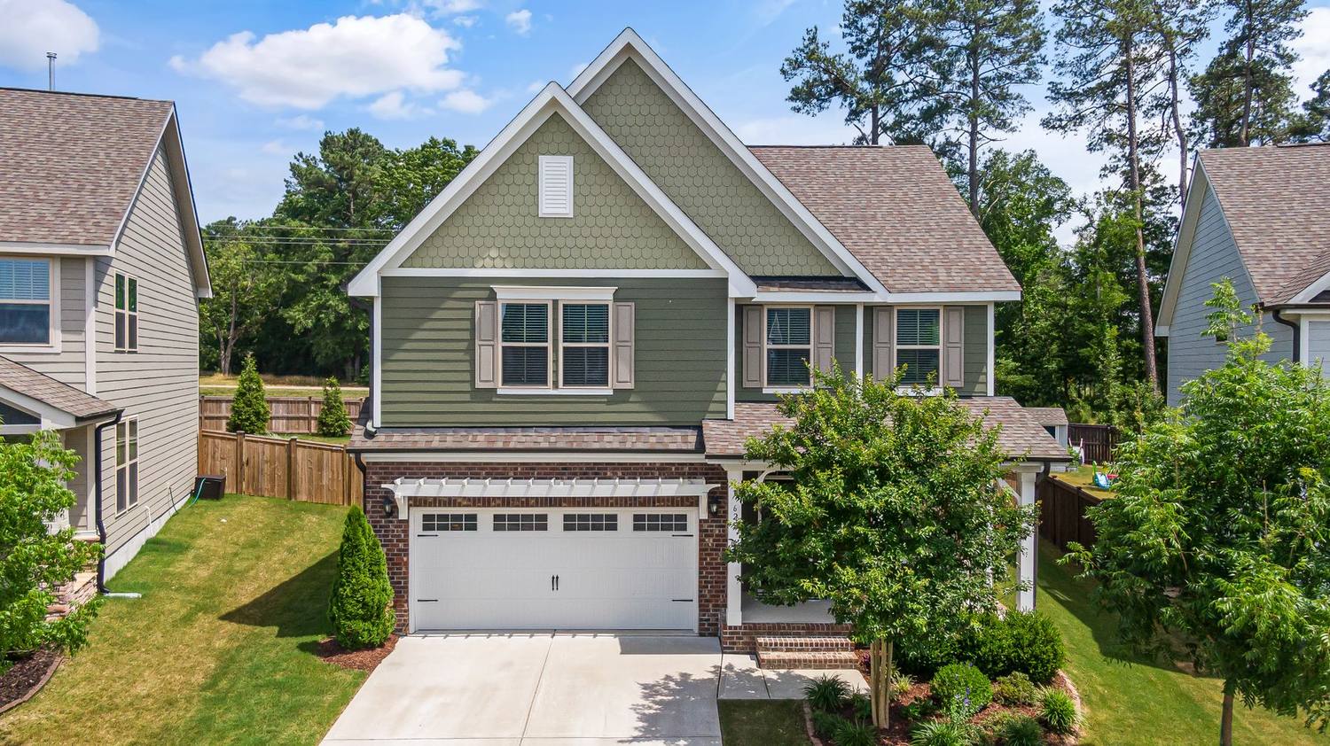 A two storey home with a freshly cut front lawn, clean driveway and trimmed shrubs.