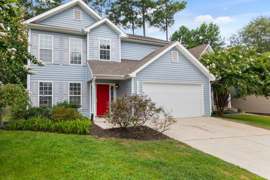 A front yard with cleared planting beds and cut grass in front of a two storey home.