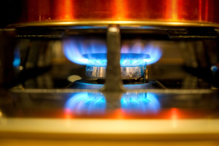 A gas burner lit under a copper bottomed pan, showing a ring of blue flame.